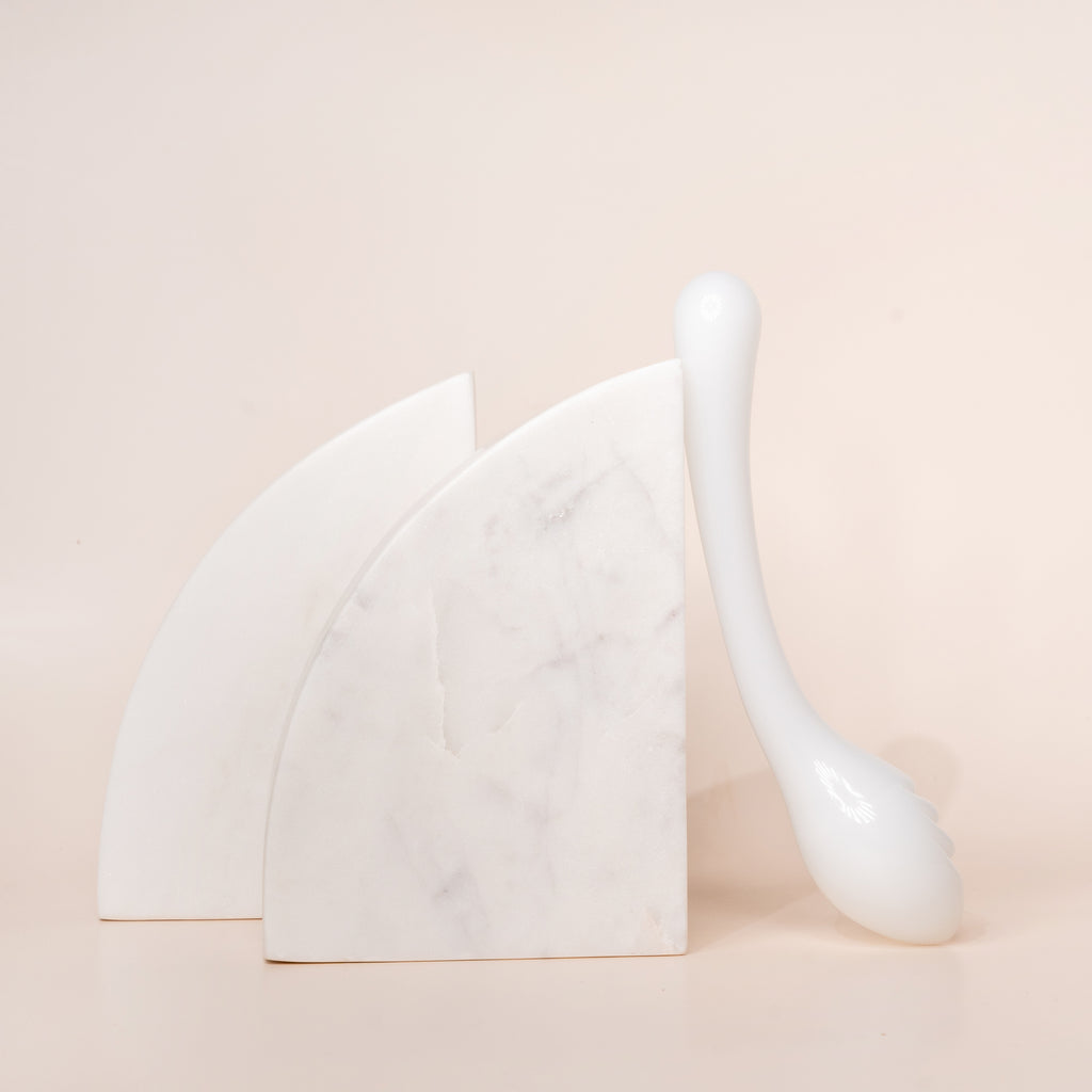 White glass pleasure wand with egg shaped tip. Pictured on beige background with marble arch blocks.