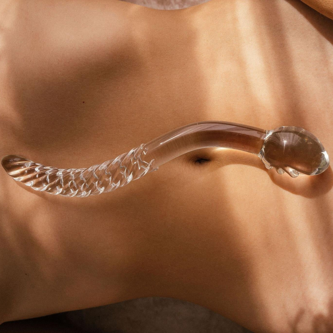 Clear cervix serpent pleasure wand 2.0 pictured on models belly. Glass pleasure wand designed for pelvic dearmouring, massage and self pleasure.